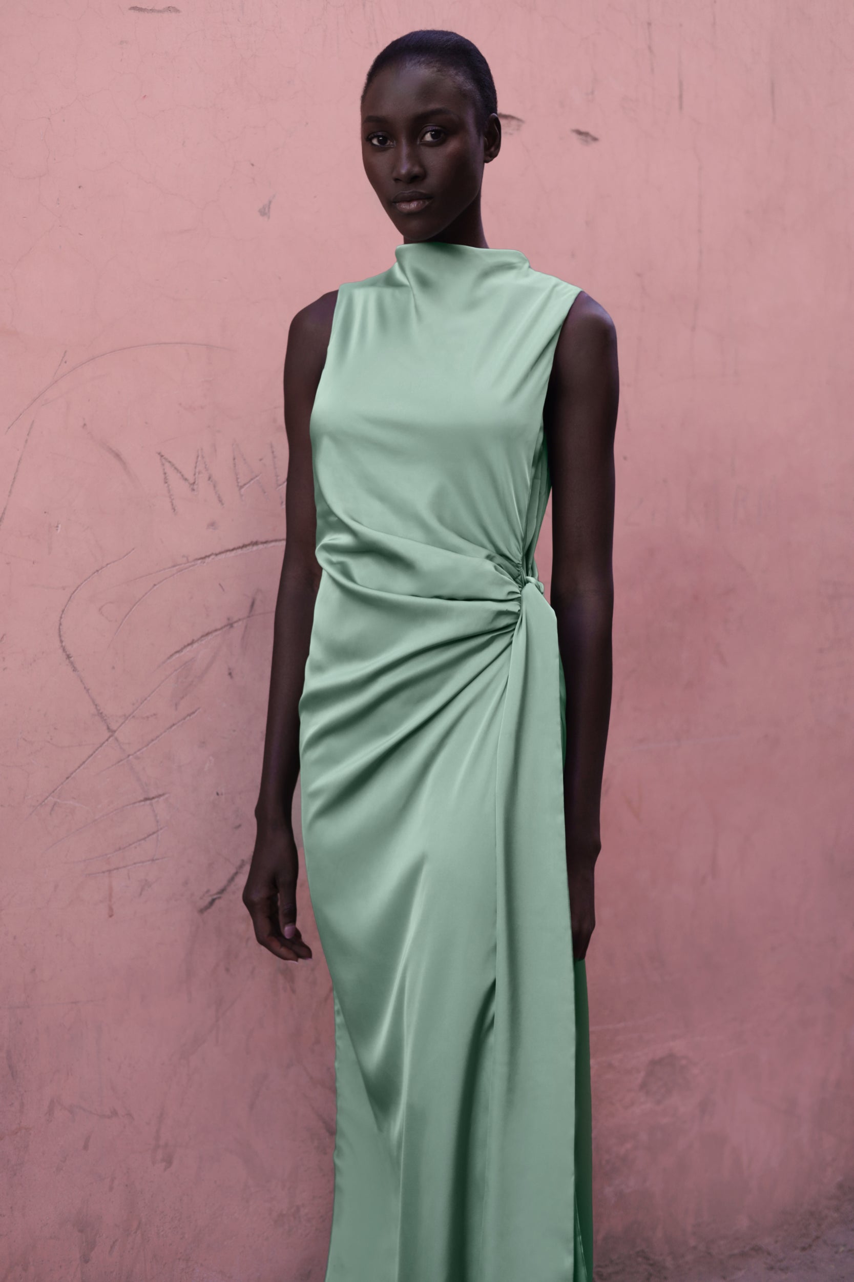 Modelo con el Baobab Vitto Maxi Dress color Jade posando frente a una pared de color rosa.