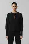 Sweater Akila de Baobab en color negro, cuello redondo con recortes frontales y herraje decorativo.