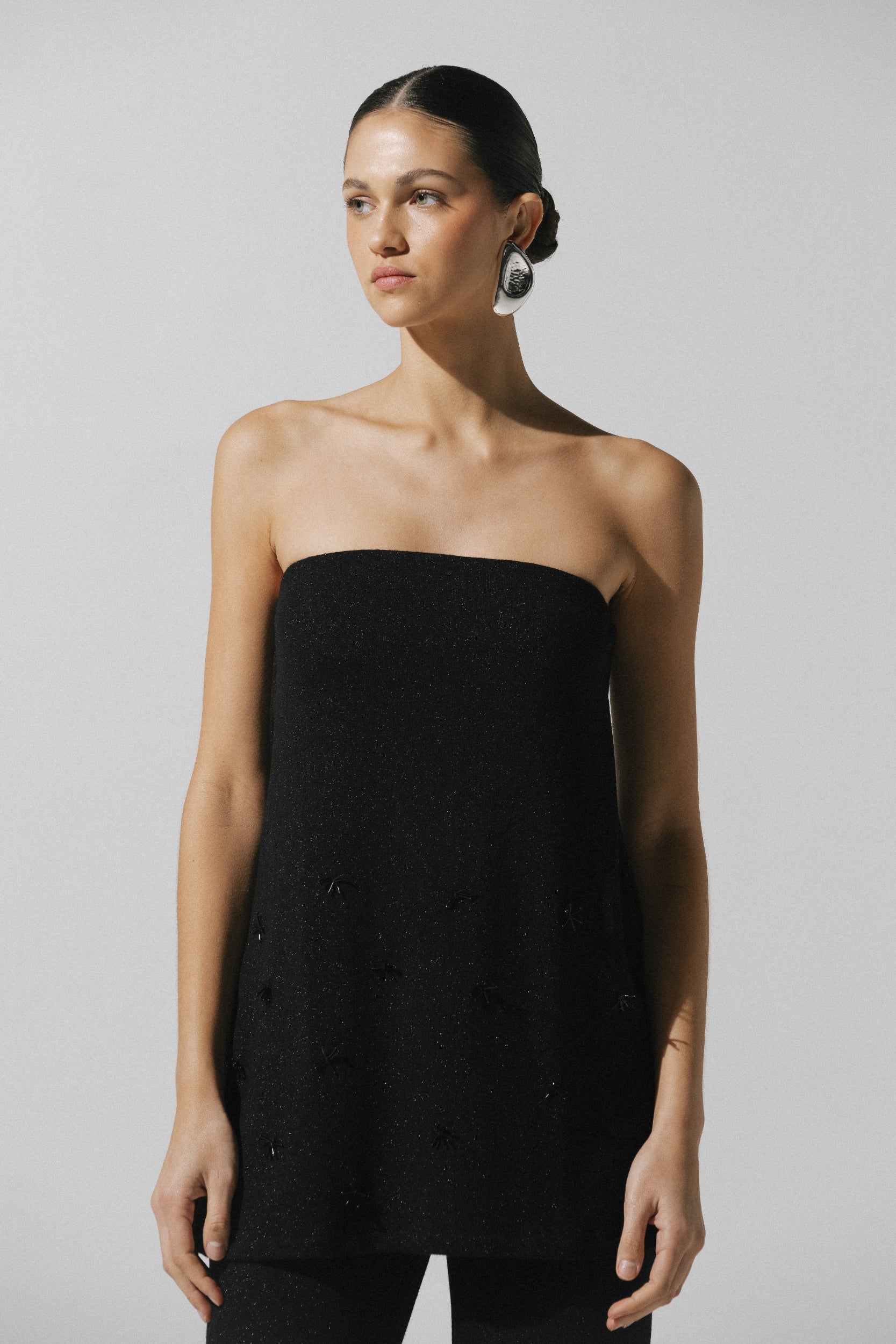 Top strapless Suzu de Baobab en tela brillante negra con bordado, combinado con pantalón.