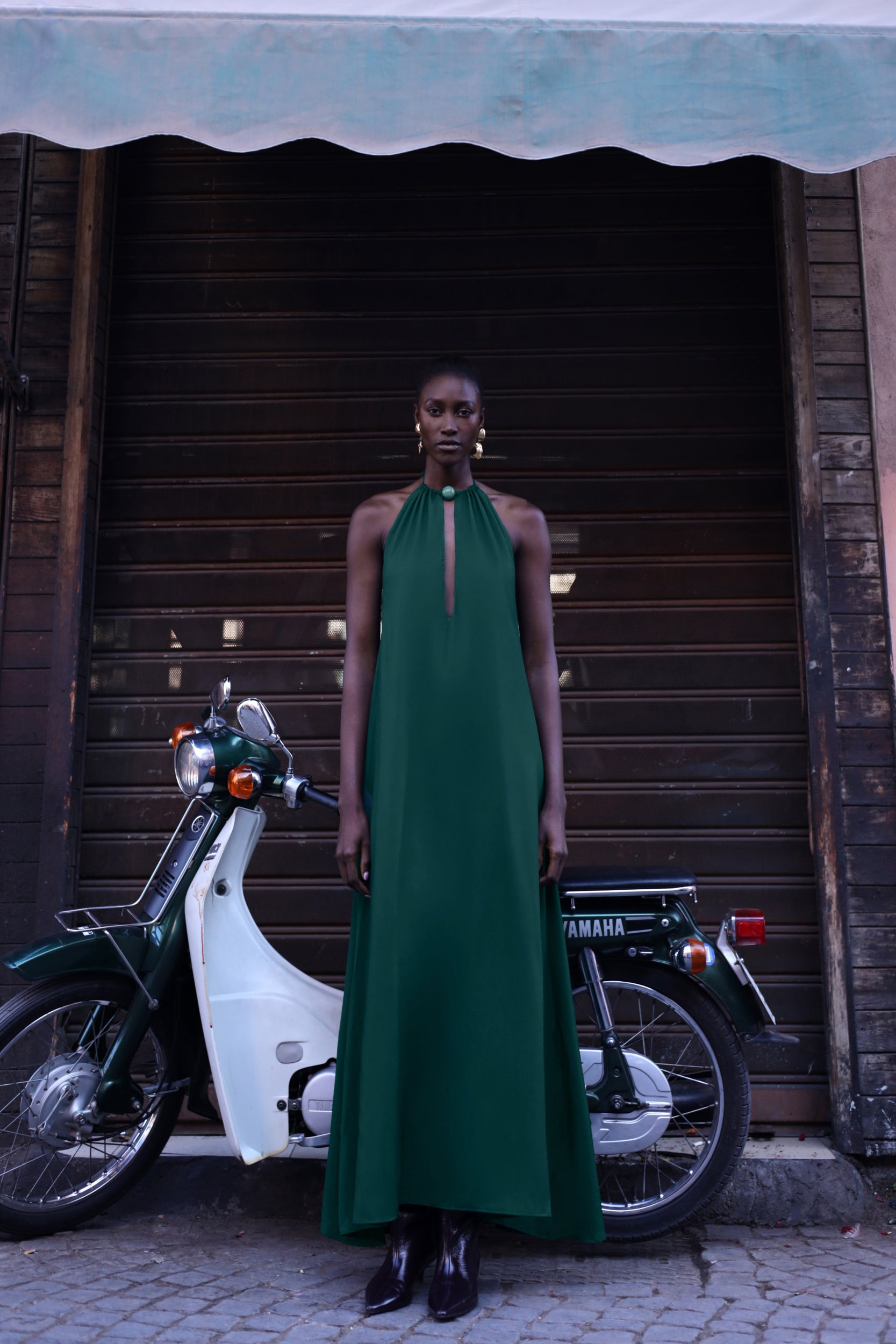 Detalle del vestido Rondine de Baobab, tela brillante y recortes frontales en color verde esmeralda.