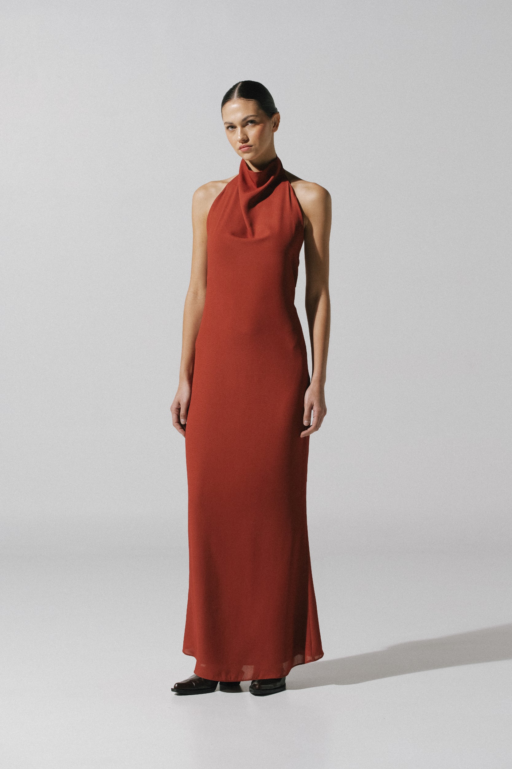Vestido maxi Consu de Baobab en color terracota, cuello halter y silueta drapeada.