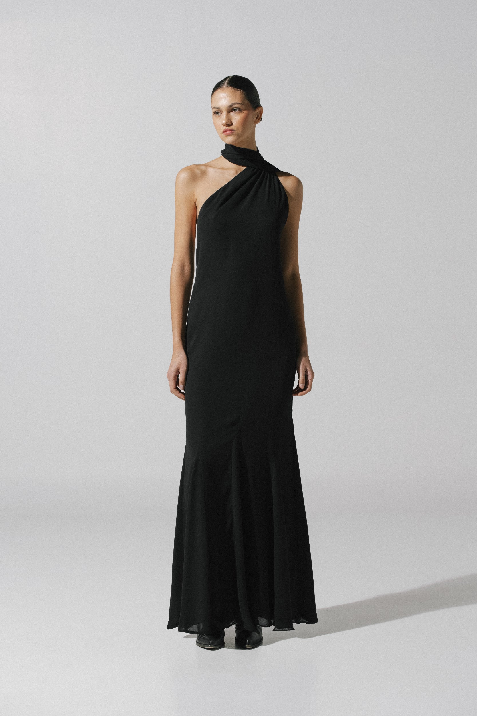Vestido negro Ari con tirante ajustable, tela fluida y godets en el dobladillo.